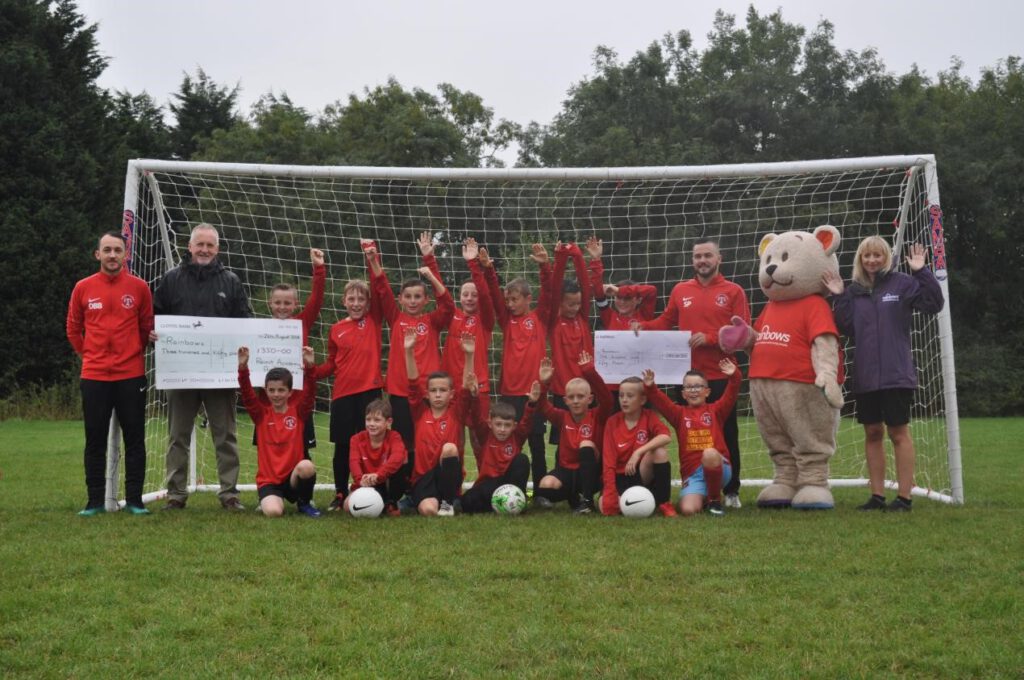 Photo of cheque being handed over to Rainbows from Alfreton Town Under 11s and Remit Training.
