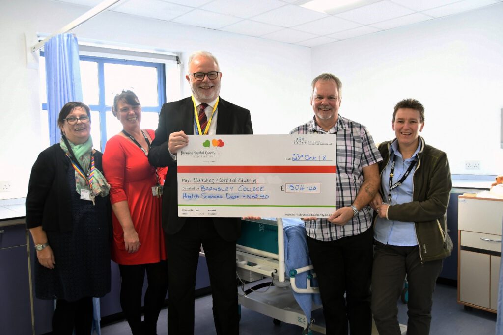 College tutor Mark Greveson (second right) presents the cheque to Barnsley Hospital Chairman Steve Wragg (centre), watched by College staff members Fran Bartleet (left), Lorraine Greveson (second left) and Jo Byrne (right).