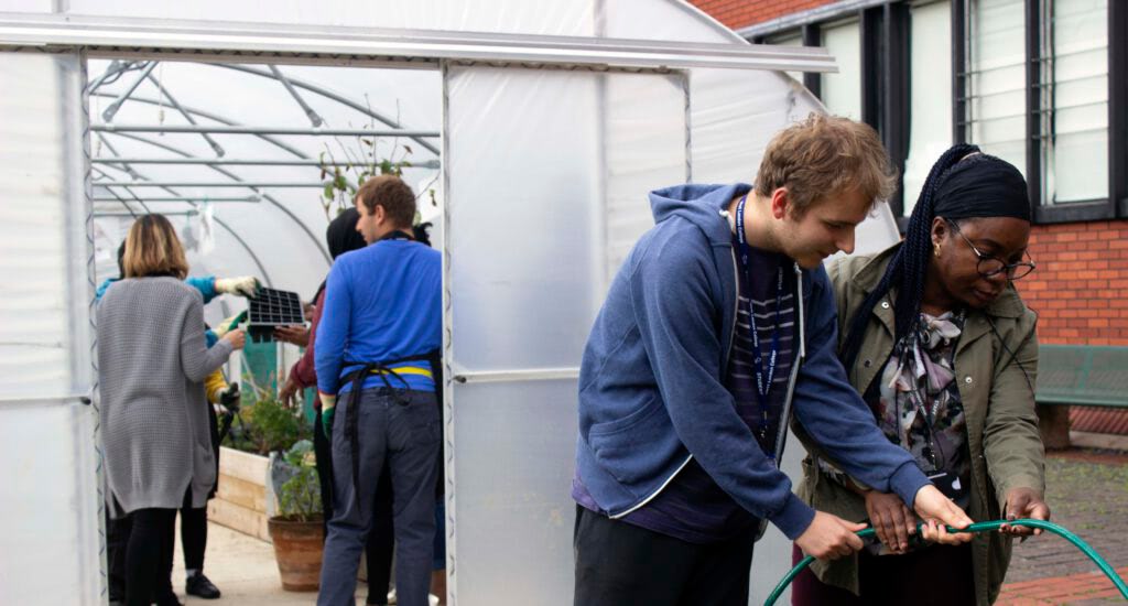 Above Inclusive Learning students and staff gardening in the greenhouse at Hammersmith & Fulham College