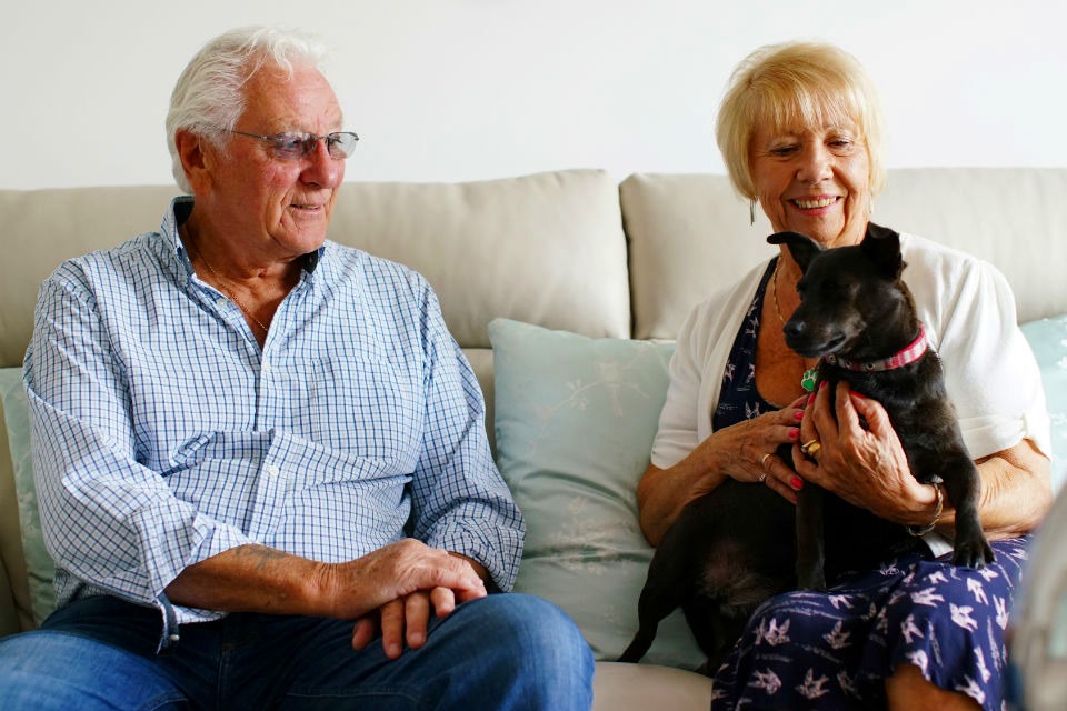 Two residents sit with a dog at one of ExtraCare's retirement villages.