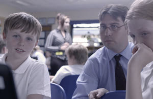 Children and teacher looking at computer.