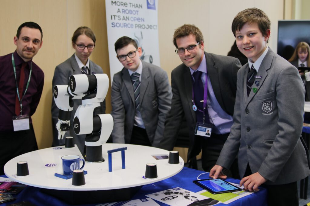 Pupils from Rugby Free engage with robotics task - Left Joshua Poolton, Comau UK; fourth from left Assistant Head Phil Kerry; fifth from left, pupil, Tom Edwards.jpg