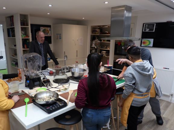 Cooking with gas: Minister Justin Tomlinson gets a few kitchen pointers from budding chefs on traineeships at Centrepoint, a leading UK charity for homeless young people.