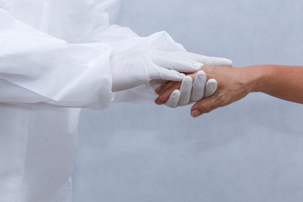 Medical gloved hand holding another hand