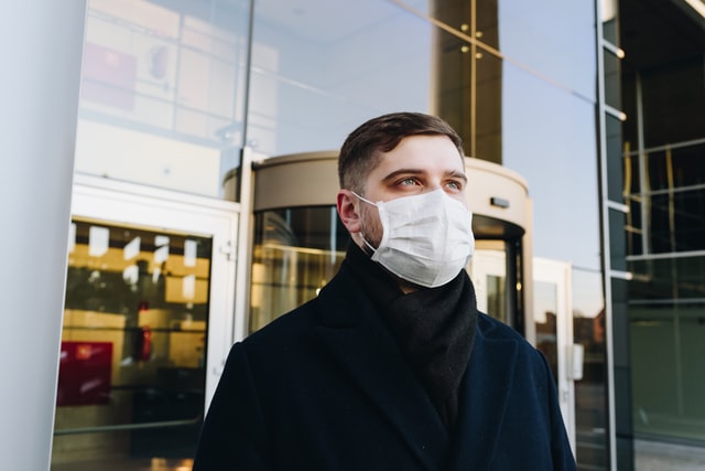 Man wearing face mask outside an office block