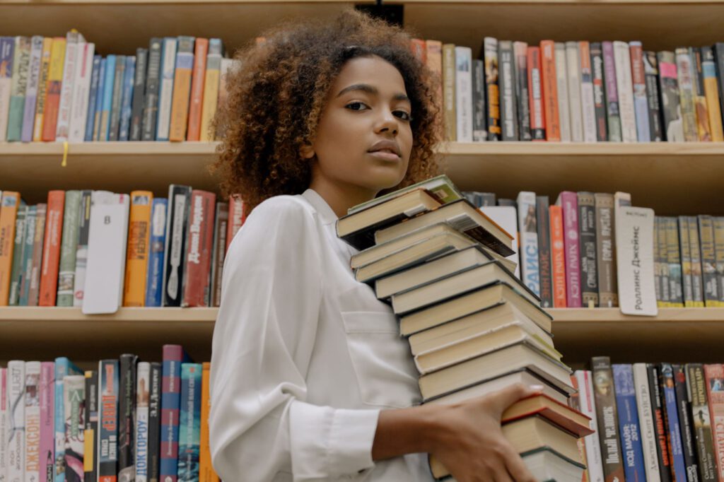 young lady carrying a pile of books