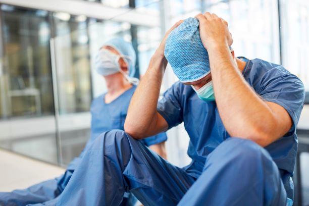 Medical professional in PPE looking stressed