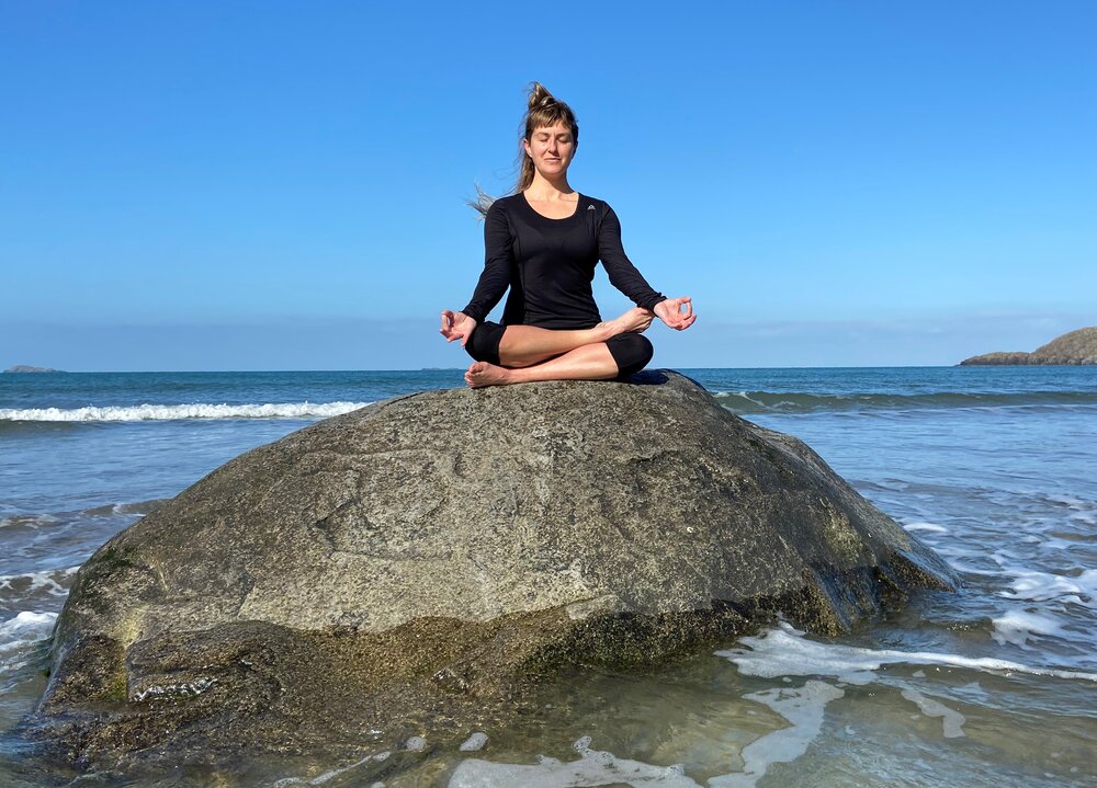 Tara Bethan sitting on a rock by the sea