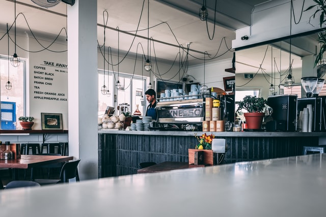 empty cafe, one member of staff behind the counter