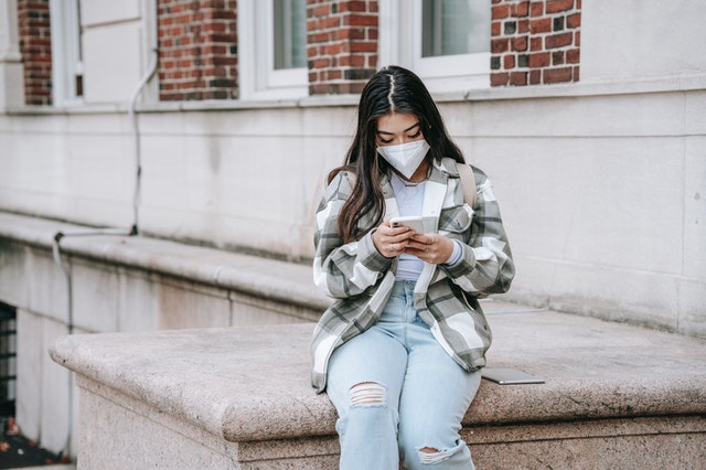 young woman in a covid mask on her phone