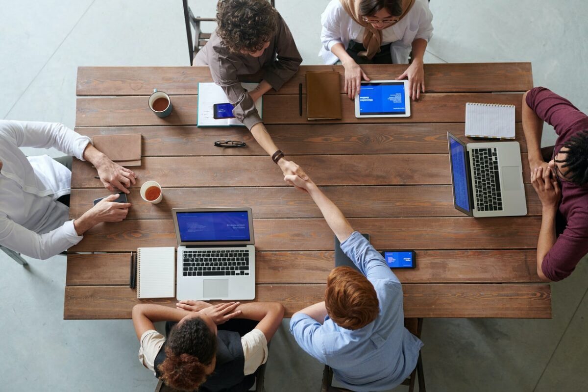 People around desk, shaking hands