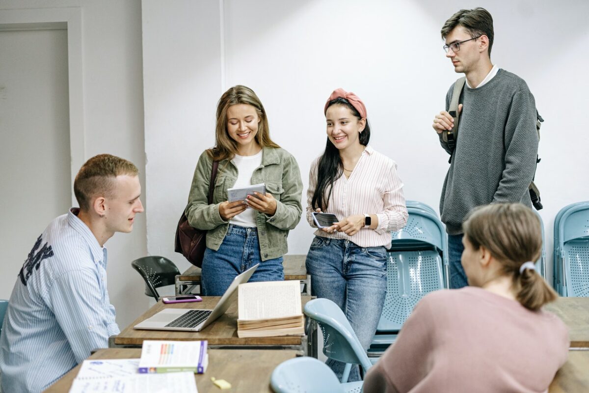 Group of students sat and stood around desk