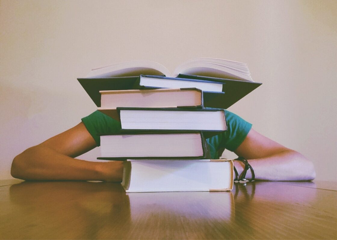 person sat behind pile of books