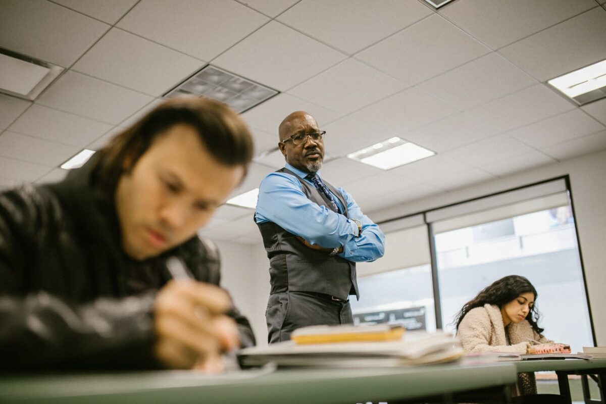 Male teacher stood watching students work