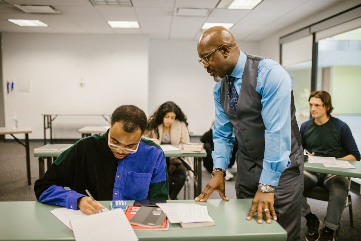 teacher looking over students shoulder at work