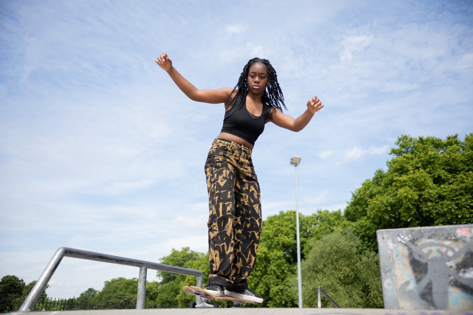 Image shows young woman skateboarding over a ramp