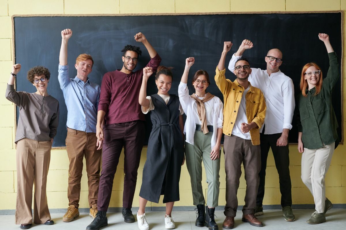 people stood in a line cheering with their arm in the air