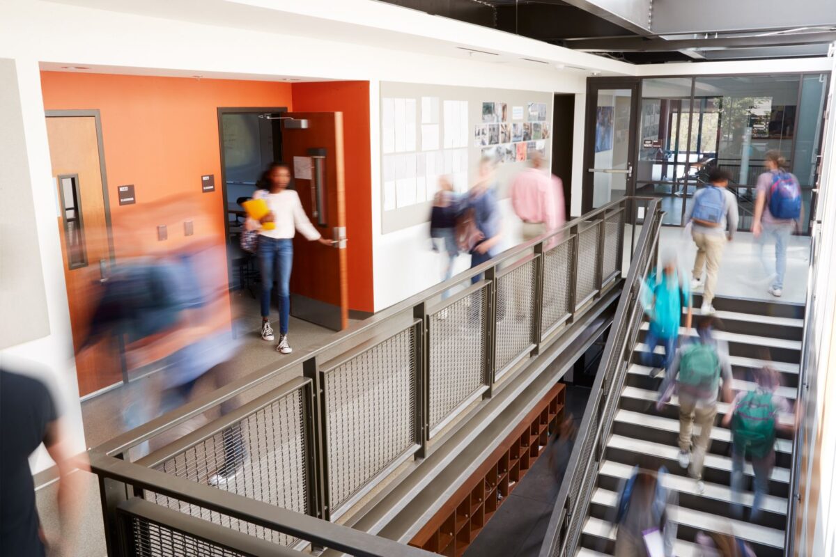 Busy college corridor with students walking in hall, up stairs