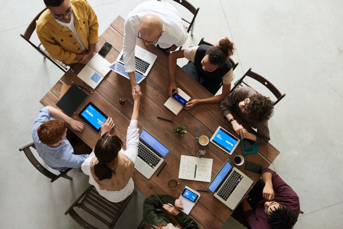 people sat around table with laptops working on project management