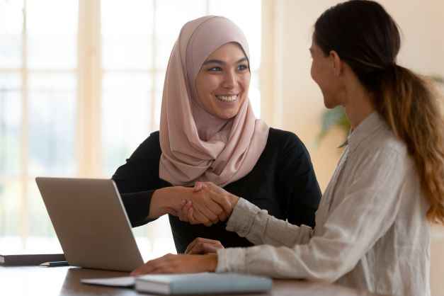 2 females talking with a laptop in front of them