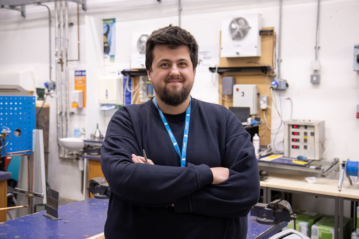 Bradford College Engineering Apprentice, James Bland, poses in an engineering workshop.