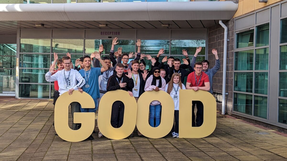 A group of students from City of Wolverhampton College standing behind giant gold letters spelling the word 'Good'