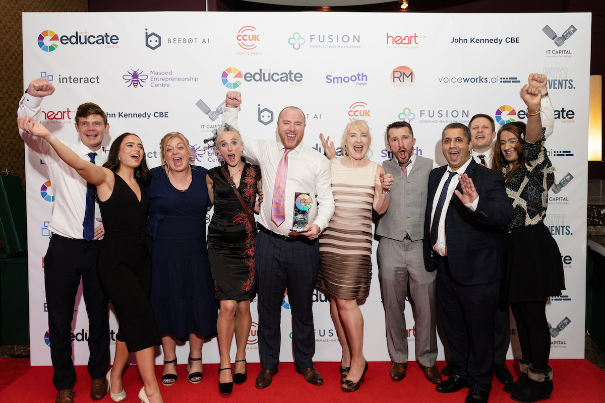 The Bradford College Progression to Learning & Work and 14-16 School Provision team punch the air celebrating while they hold their Student Experience trophy at the Educate North Awards 2023.
