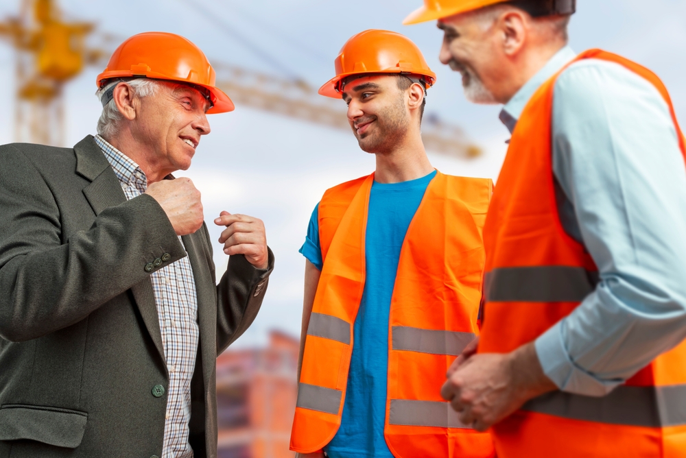 Older construction worker on construction site talking to younger workers