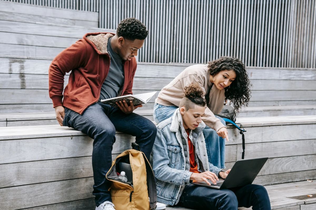 students sat on steps with books and laptops