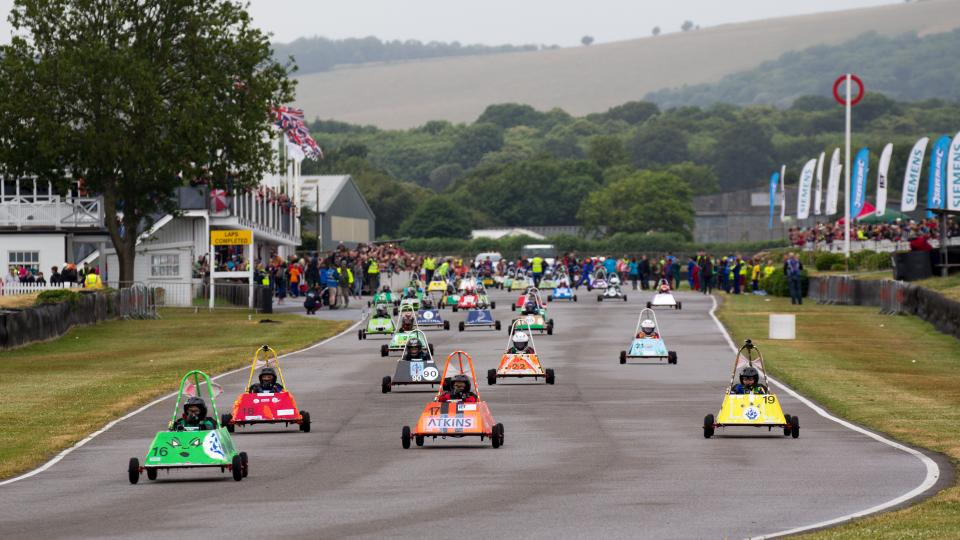Electric kit cars race around an outdoor track.