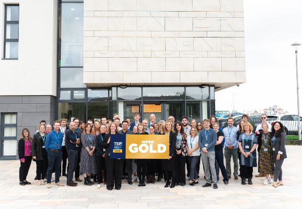 UCW staff stood outside Winter Gardens campus with We are Gold Sign