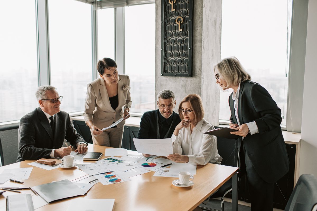 men and women sat around a table at work looking at reports