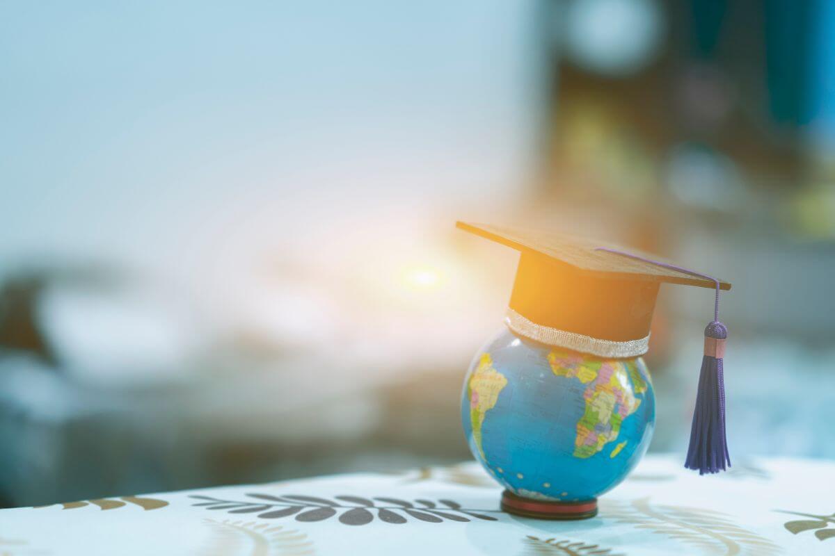 A small globe positioned on a desk with graduation cap.