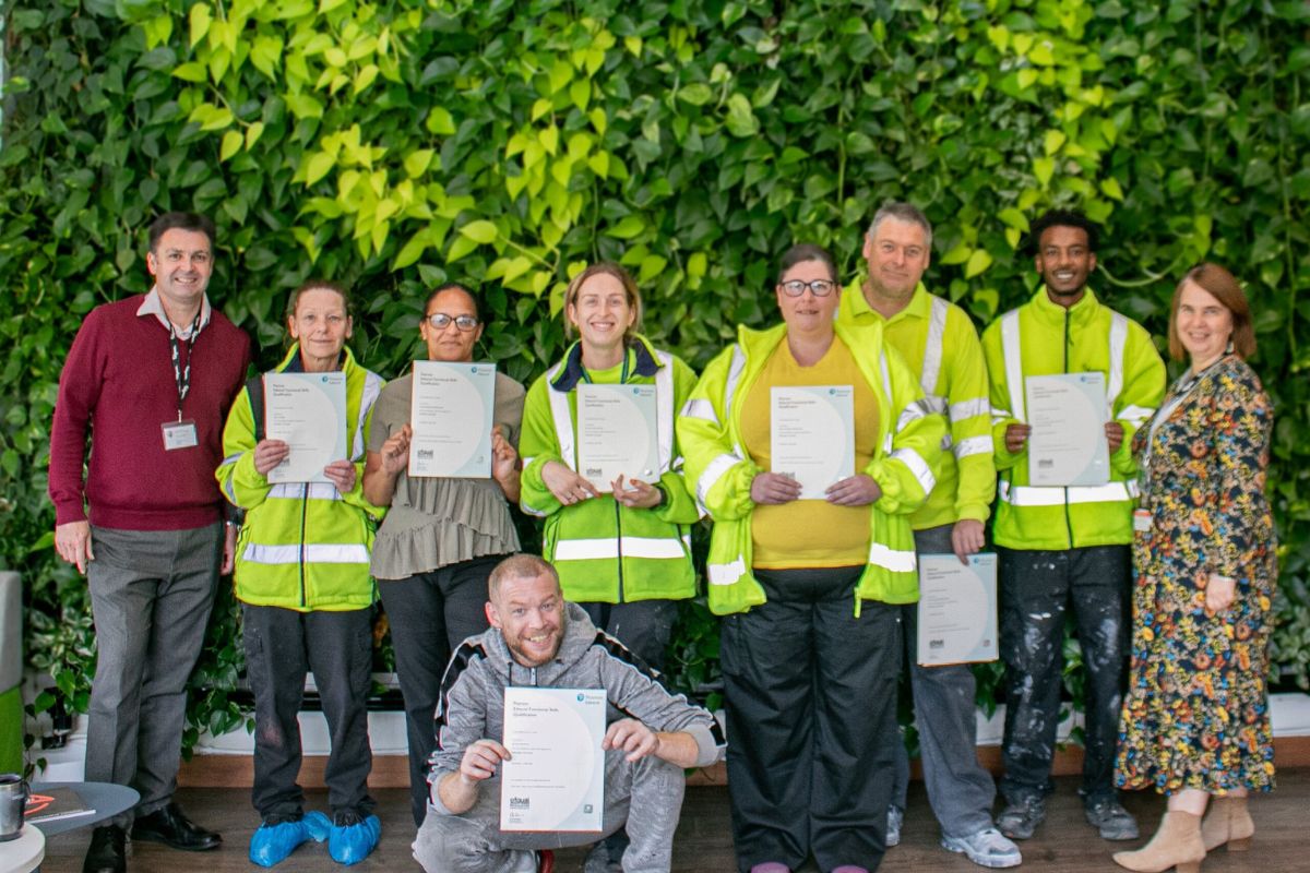 Polyseam employees pose with their programme certificates in front of forest wall