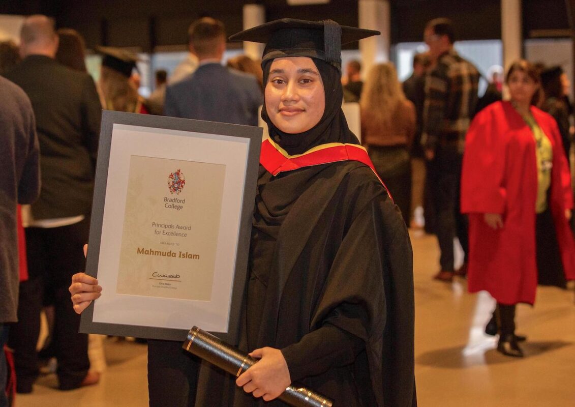 BSc (Hons) Ophthalmic Dispensing graduate Mahmuda Islam stands in her graduation cap and gown and holds her scroll and a framed award certificate.