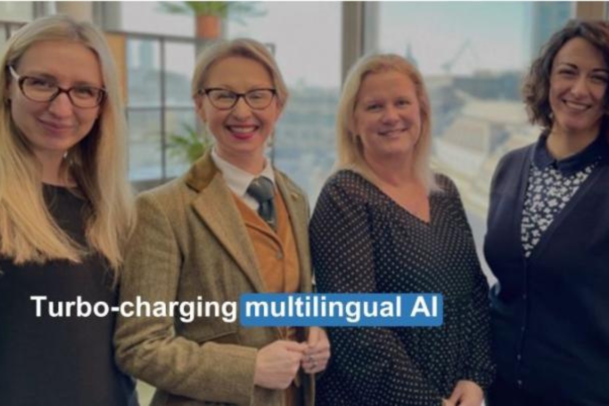 Image of four of Guildhawk's female leaders smiling for the camera. From the left they are Rita Hinterleithner, CEO Jurga Zilinskiene MBE, Mia Campbell and Giorgia Romani Head of Technology innovations. Over the image are the words 'turbo-charging multilingual AI'. Image used in FE News post Feb 2024.