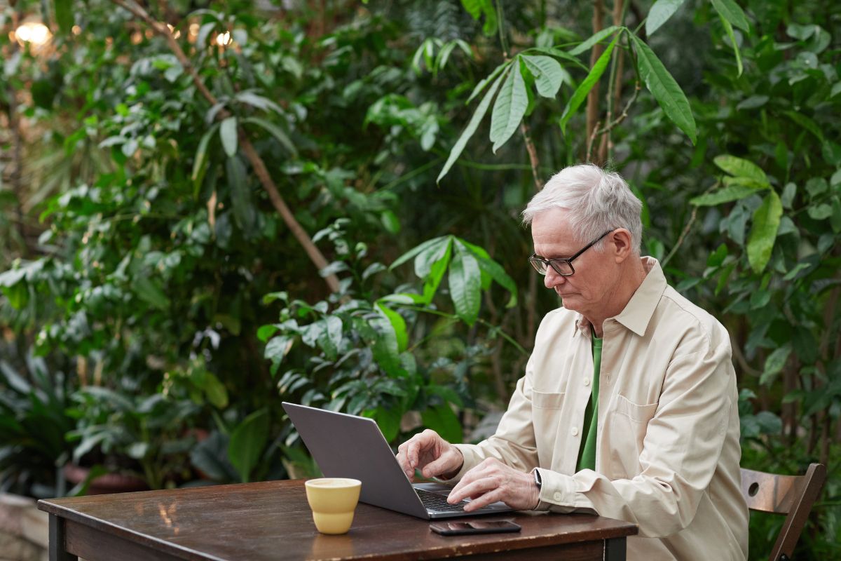 Older aged man on laptop working outside