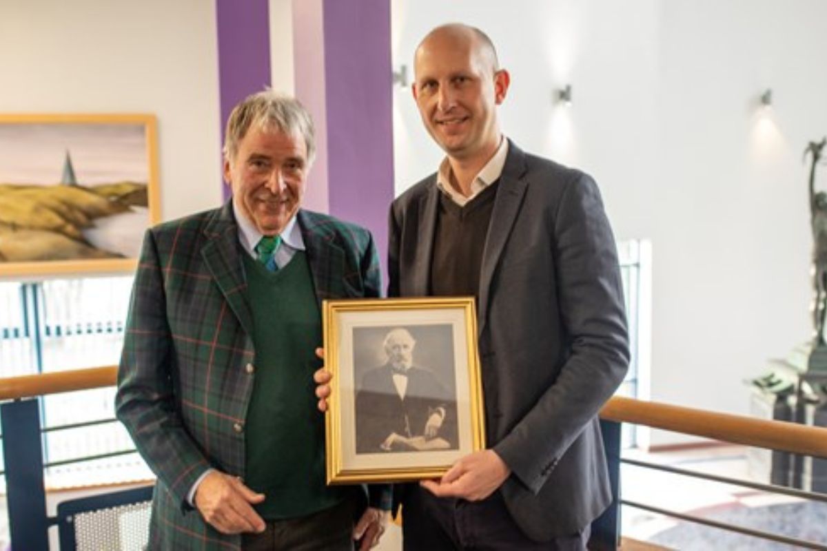 two men stood holding photo frame