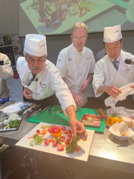 A group of chefs preparing food  Description automatically generated