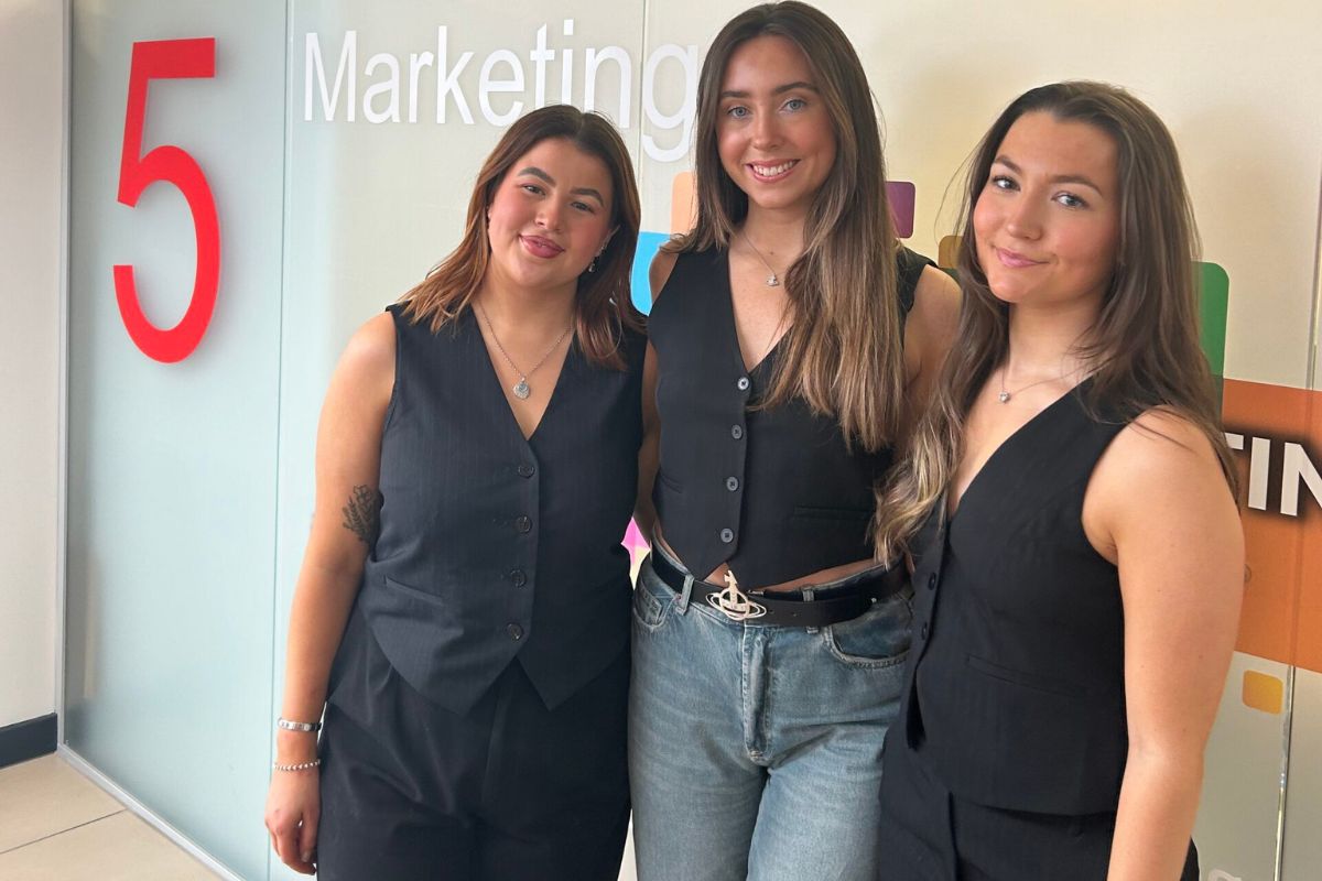 3 girls sending next to each other smiling