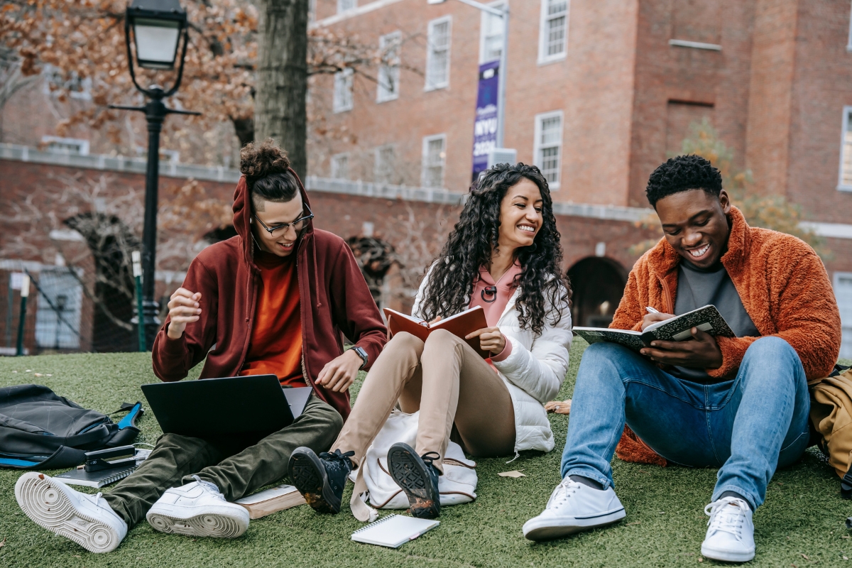 students sat on some grass laughing