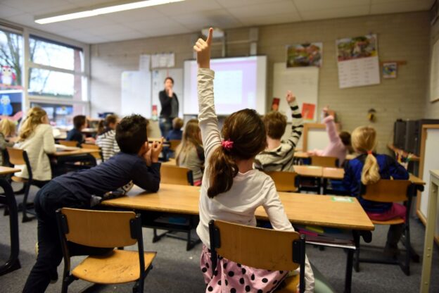 classroom, with pupils with their hands up, picture taken from the back of the room