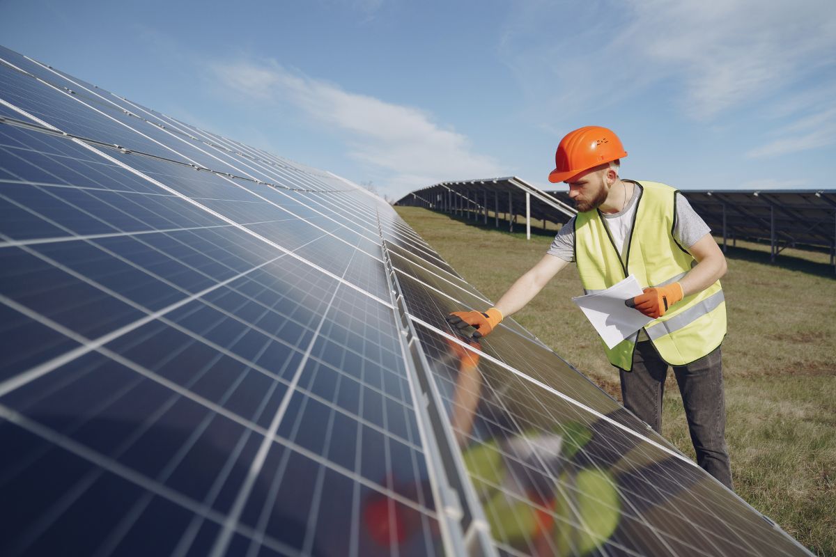 man in hard hat touching a row of solar panels, pexels, stock