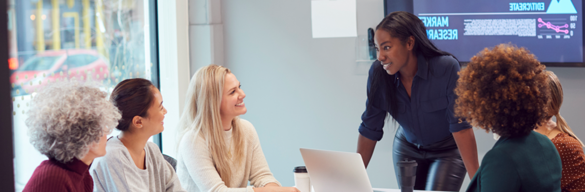 Students speaking around a table with a laptop