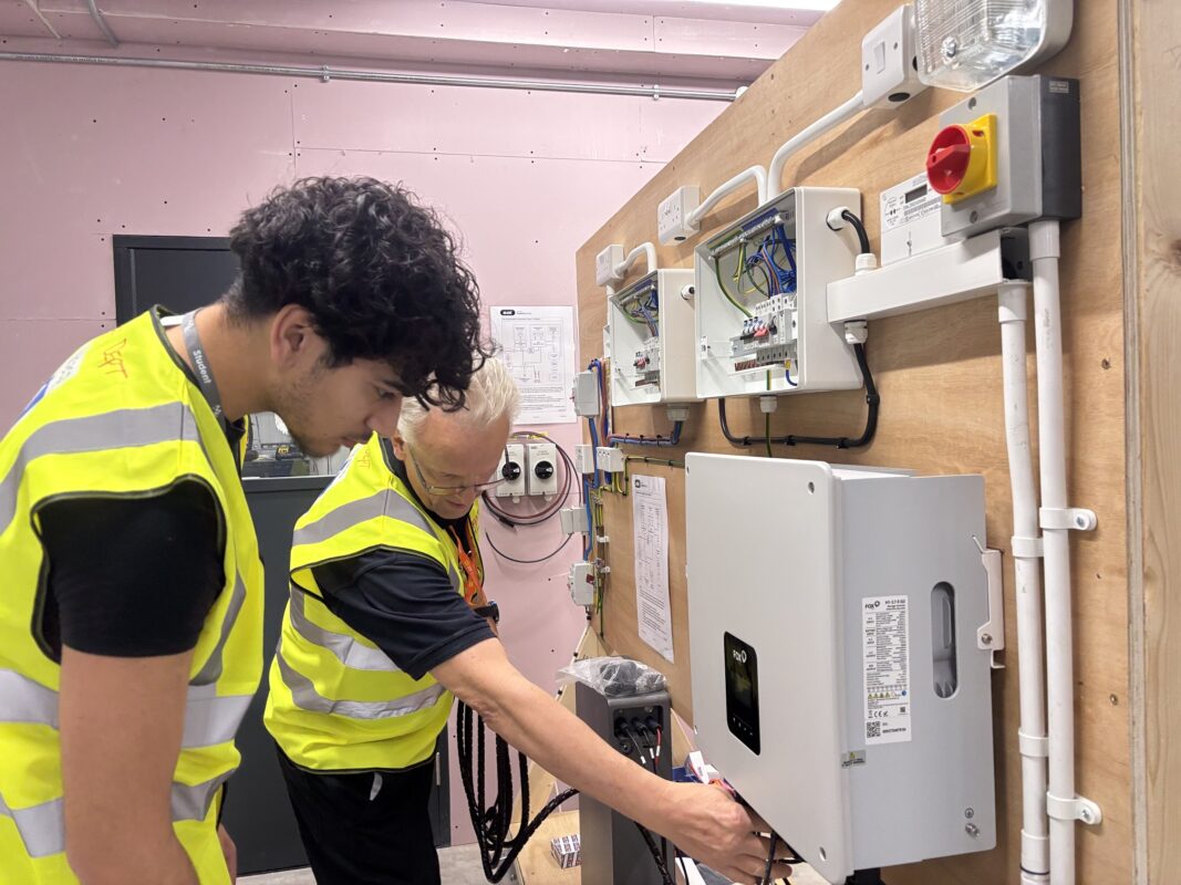 Lecturer, Andy Mallett shows Mason Majethia how to connect up a battery storage unit