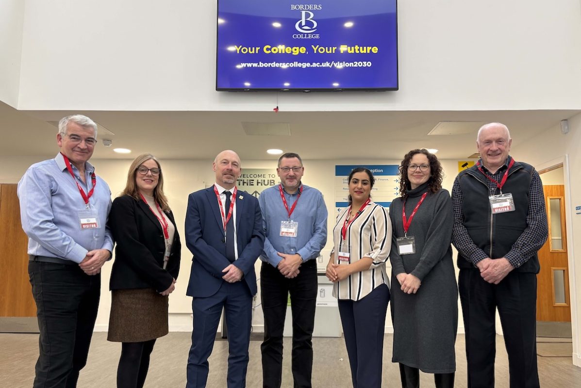 Group photo of seven people standing in a college reception area