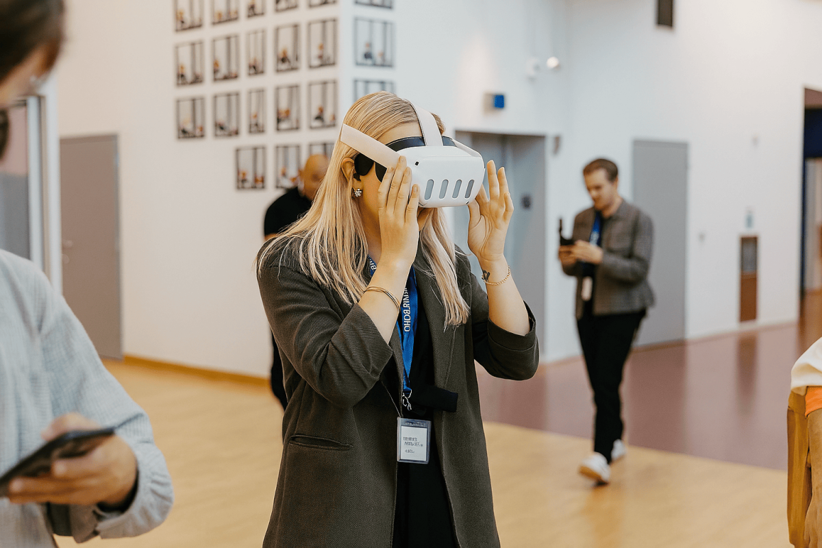 A women wearing a virtual reality headset stands in a room with people walking around her.
