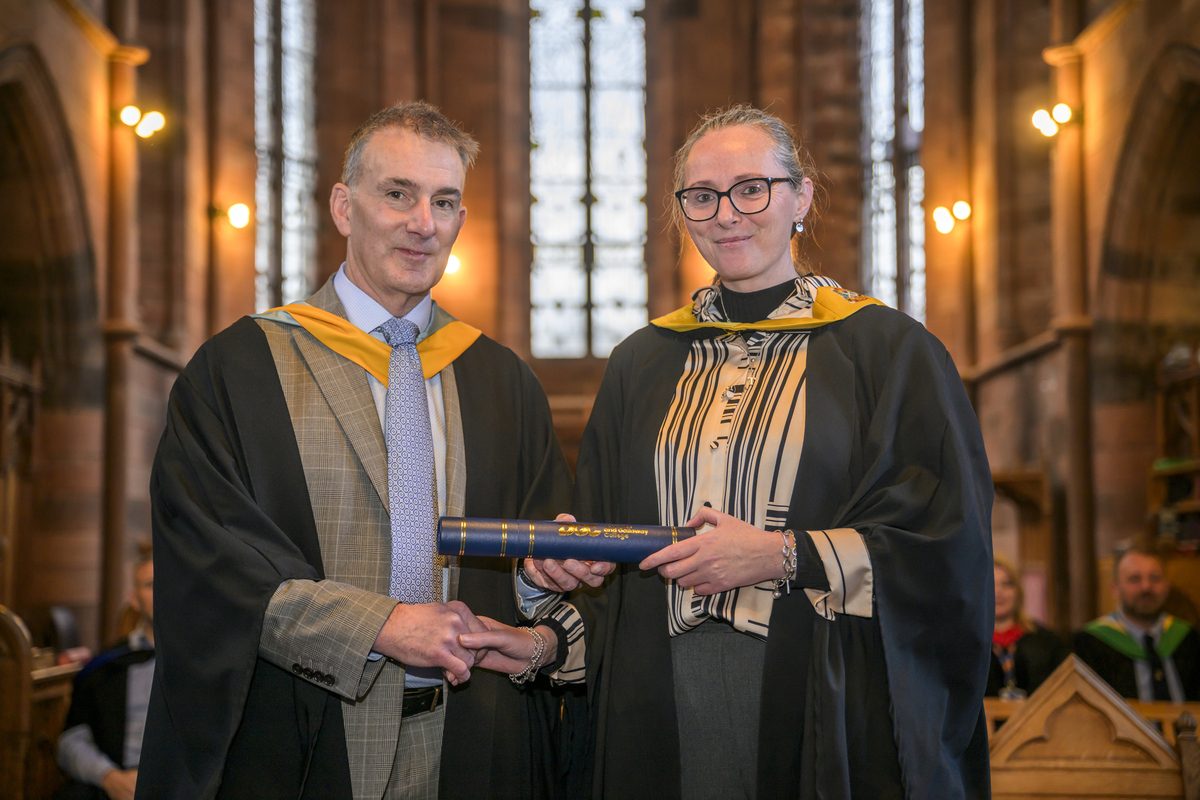 Student Atina Patterson collectinga her scroll from Principal Douglas Dickson
