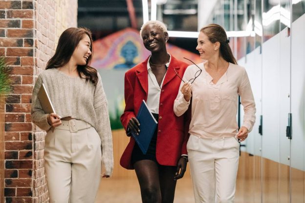 stock three women walking in an office and laughing