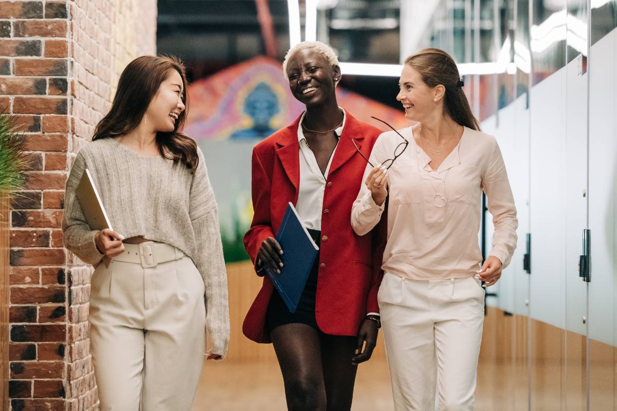 stock three women walking in an office and laughing